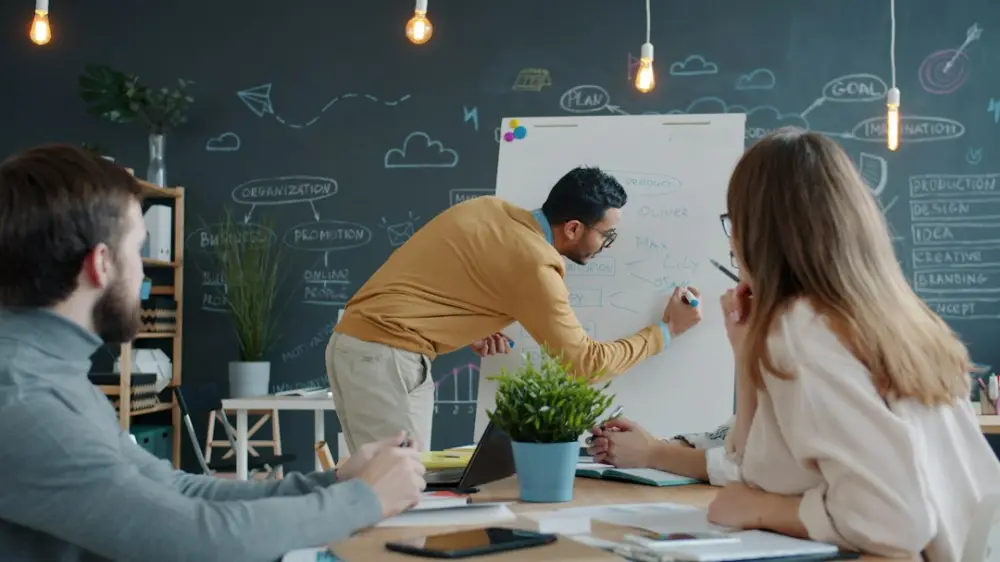 Man presenting ideas on whiteboard to colleagues, illustrating turning ideas into practical business action
